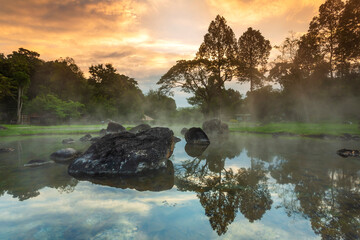 Hot springs over rock terrain with misty and morning sunrise rays and Natural Mineral Water of Chae Son National Park in Lampang Province, Thailand.