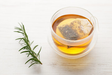Cup of hot tea blended from rooibos, spearmint, apple, baobab on white wooden table.