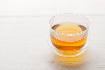 Cup of hot tea blended from rooibos, spearmint, apple, baobab on white wooden table.