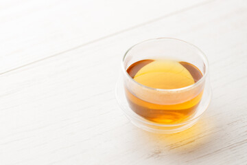 Cup of hot tea blended from rooibos, spearmint, apple, baobab on white wooden table.