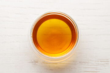 Cup of hot tea blended from rooibos, spearmint, apple, baobab on white wooden table.