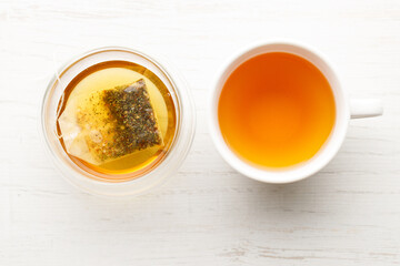 Cup of hot tea blended from rooibos, spearmint, apple, baobab on white wooden table.