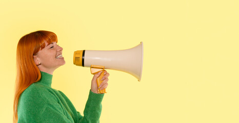 Woman enthusiastically shouting into a megaphone against a vibrant yellow background