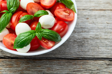 Basil leaves , cherry tomatoes and mozzarella cheese . In bowl food photography