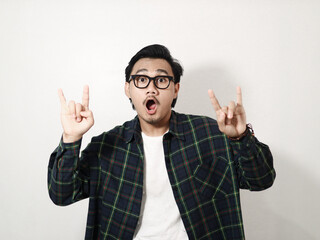 A young Asian man in a plaid shirt smiles and makes a hand sign for "I love you" in American Sign Language against a matching white background.
