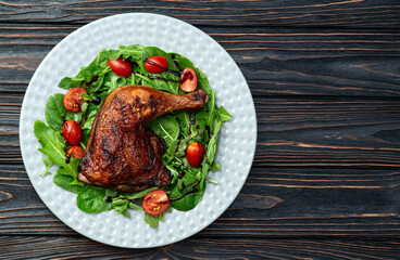 Grilled chicken legs with tomatoes and salad . Top view