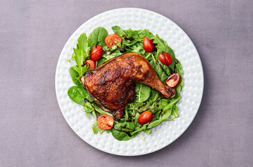 Grilled chicken legs with tomatoes and salad . Top view