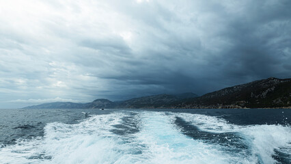 Turquoise wave and dramatic clouds on the coast, Mediterranean Sea, Sardinia