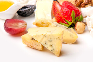 Cheese plate beautifully laid appetizer in a restaurant, Cheese, nuts and berries on a white background.