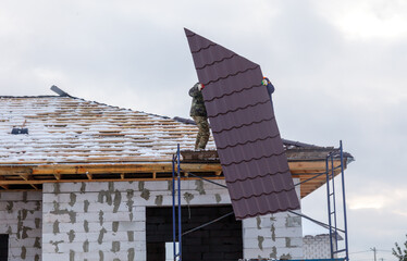 A man is working on a roof with a piece of metal