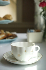 White porcelain teacup on table with pastries in background