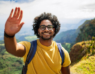 Fototapeta premium Young Man Waving from a Mountain Trail with Scenic Views