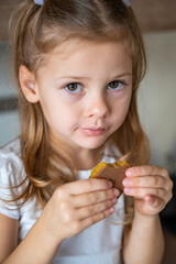 Little girl eating Dubai chocolate with pistachio paste and kataifi dough. Confectionery handmade sweets at home in the kitchen. 