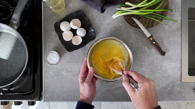 Top view a hand men mix up chicken eggs to make omelette in the morning in home kitchen.