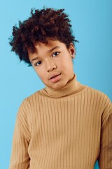 A young african american boy in a turtleneck sweater gazing intently at the camera with a...