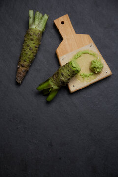 Grater and grated horseradish on a black stone baking sheet