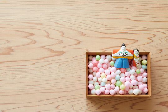 Hina dolls and arare in a bowl on a wooden tabletop