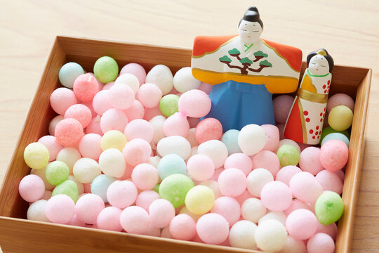 Hina dolls and arare in a bowl on a wooden tabletop