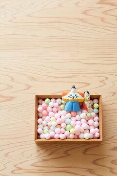 Hina dolls and arare in a bowl on a wooden tabletop