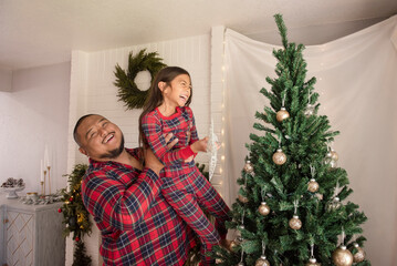 Father and daughter laughing in front of christmas tree