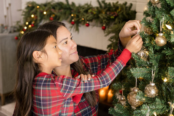 Mother and daughter decorating christmas tree together