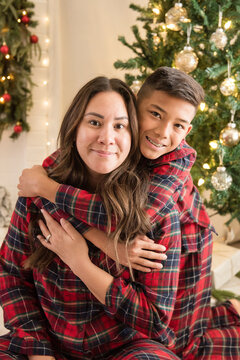 Son hugging mom in front of christmas tree