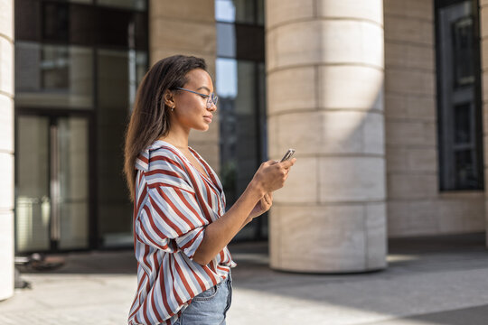 Latin young woman use mobile phone on urban street