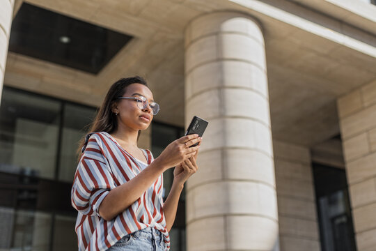 Latin young woman use mobile phone on urban street