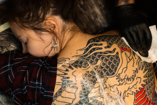 Close up hands of an artist tattooing customer's back. Irezumi tattoo
