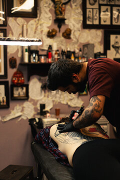 Tattoo artist doing Japanese traditional tattoo on woman's back