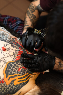 Close up hands of an artist tattooing customer's back. Irezumi tattoo