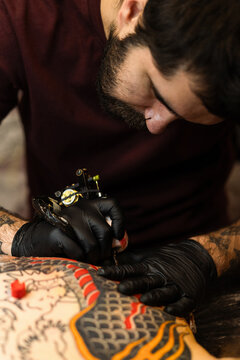 Close up hands of an artist tattooing customer's back. Irezumi tattoo