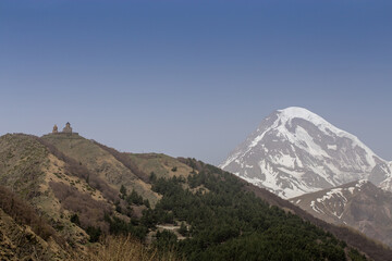 Obraz premium A breathtaking view of Mount Kazbek in Georgia, with its snow-capped peak rising majestically under a clear blue sky.