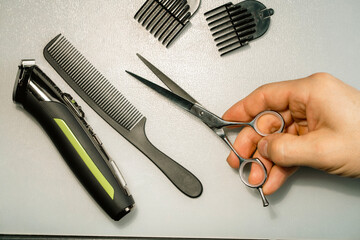 Hairdresser's hands holding hair cutting tools on white background.