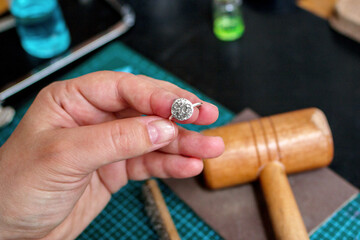 Hands of woman holding a silver rings with a unique handmade design in an jewelry workplace.