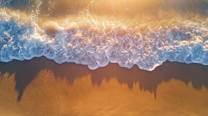 Fine beach sand with delicate wave patterns glistening under golden sunlight, shot from above