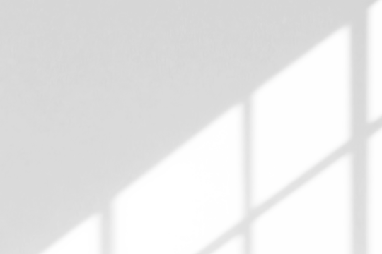 A minimalist image with soft, diffused light casting geometric shadows through a window onto a bare surface.
