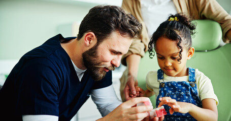 Dentist, teeth model and man with child in clinic for cleaning, dental hygiene and gum wellness. Healthcare, dentistry and young patient with hygienist for consulting, oral care and medical services