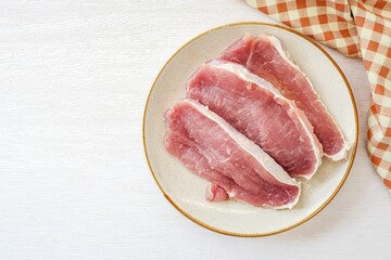 Sliced pork in ceramic plate on a white background, top view	
