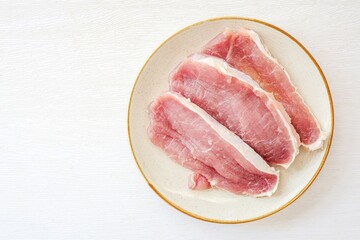 Sliced  pork in ceramic plate on a white background, top view
