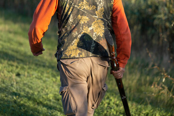 Mature hunter man holding a shotgun and walking through a field