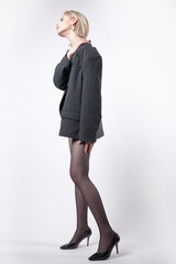 Business lady in a suit with amazing long legs in tights in the studio.