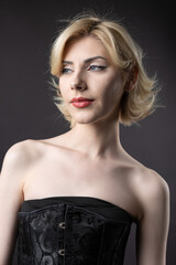 Naklejka premium Expressive young blonde under a bob in the studio. In a black corset and dress.