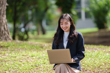 Asian independent woman, beautiful smiling student, doing business, studying Outdoors with laptop, interacting with customers on social media, studying online. Fashion concept, modern technology.