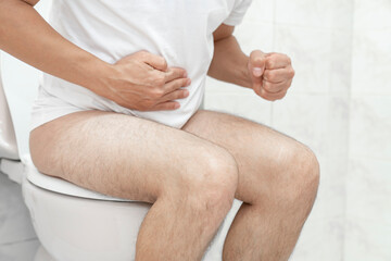 Sitting on toilet with suffering from constipation or hemorrhoid. Feels uncomfortable in his...