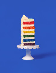 Rainbow cake slice isolated on a blue background.
