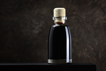 Bottiglietta di aceto balsamico, condimento tipico di Modena, isolata su fondo scuro, primo piano