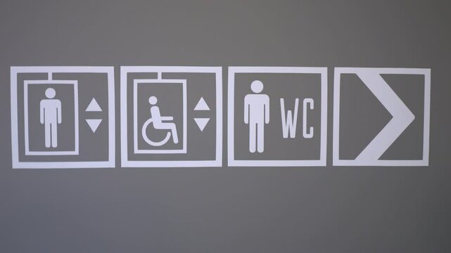 Signage for Public Restrooms Featuring Symbols Indicating Accessibility and Lift Usage