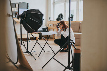 Female photographer taking photo of objects on background in photo studio with professional...