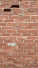 Fototapeta premium Weathered red brick wall with cracks and missing mortar, giving a rustic and aged look, red